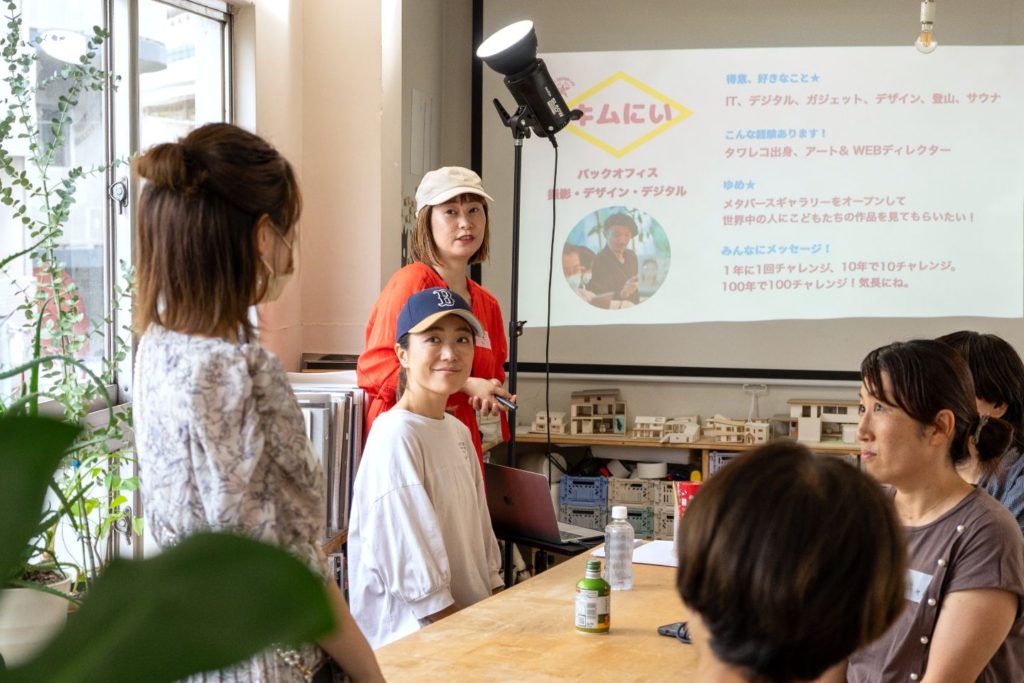女性たちが集まり、プロジェクターの投影を見ながら話している