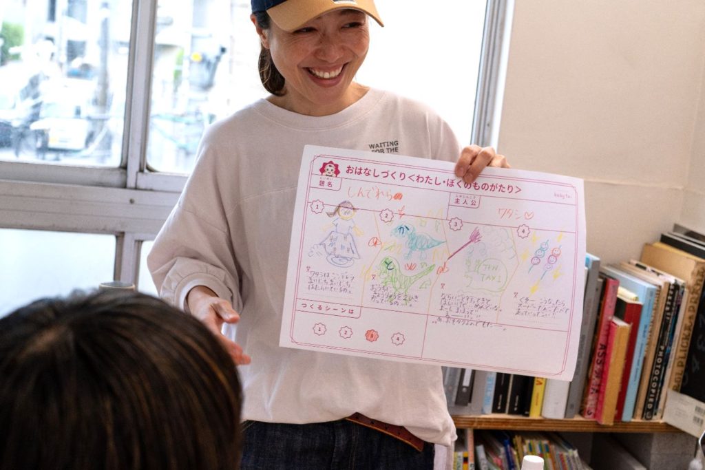 女性が子供の絵が描かれた物語シートを笑顔で見せている
