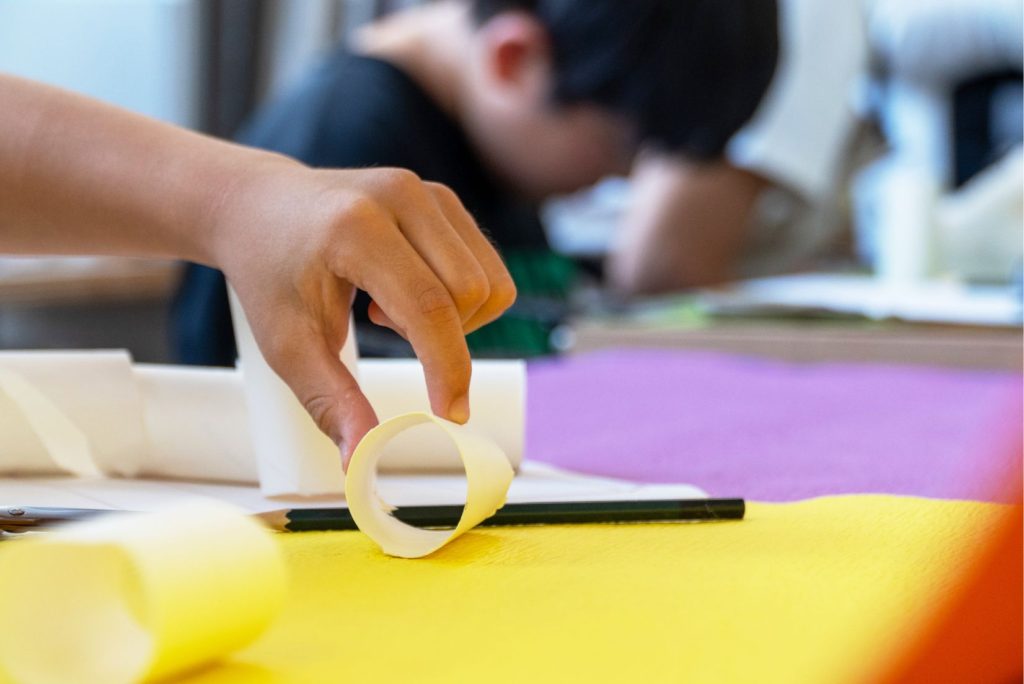 子どもが紙筒を手に持ち、制作活動をしている様子