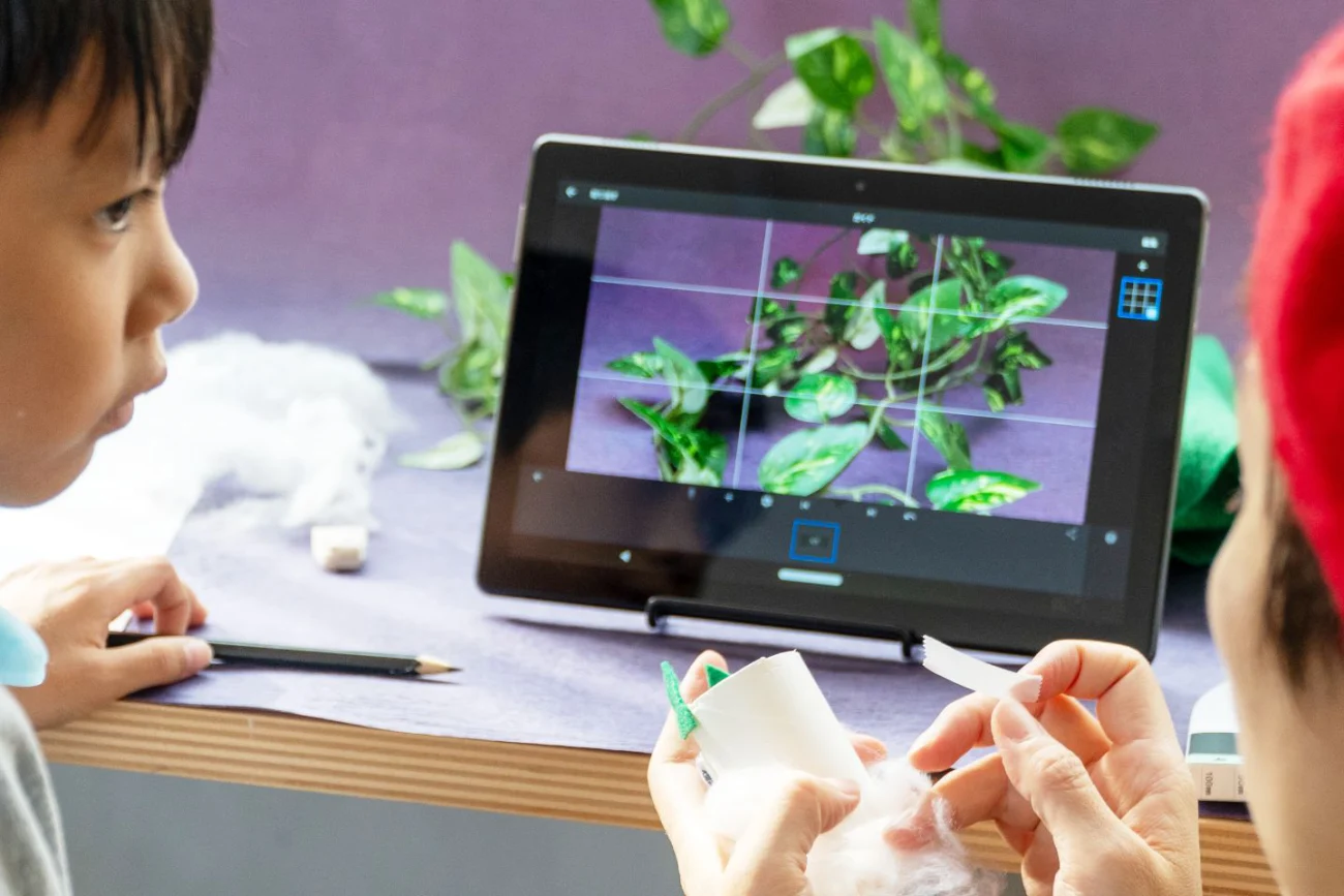 子どもたちがタブレットで植物を撮影し、工作をしている様子