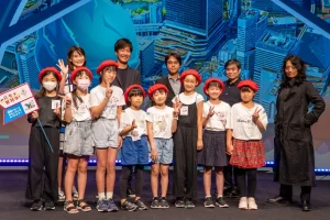 赤いベレー帽をかぶった子どもたちと大人たちが並んでポーズをとっている