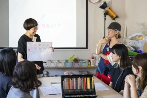 女性講師が子どもたちにアート教材を説明する様子